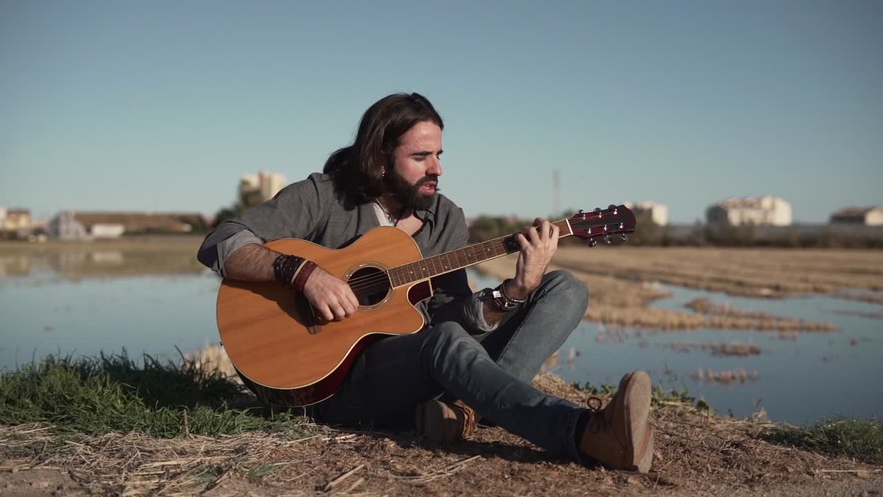 Mann spielt Akustikgitarre auf einem Feld