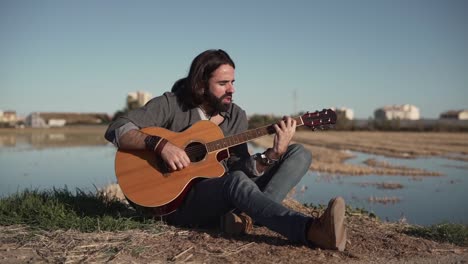 man playing acoustic guitar in a field