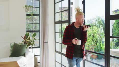 Albino-african-american-man-with-dreadlocks-using-smartphone-and-looking-at-the-window