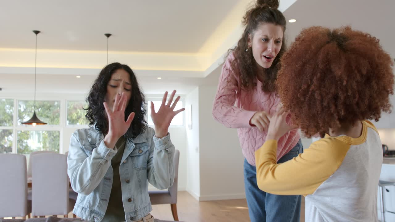 Amiche che ballano su un cuscino a casa mentre l'amica al centro esulta, celebrando l'amicizia