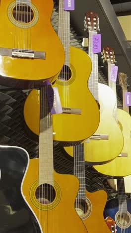 a large selection of acoustic guitars in the music store. stringed musical instruments. vertical video