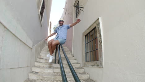 slider shot of happy man sliding down railing in street