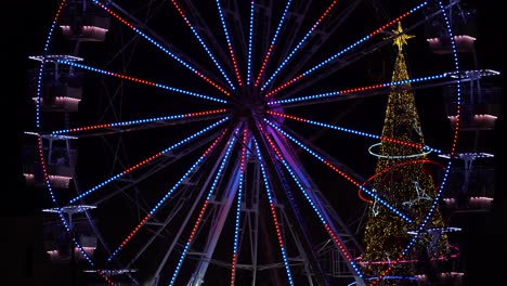 ferries wheel and new year tree illuminated by colorful lights on night sky background