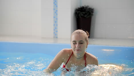 Cute little baby and his mother having swimming lesson in the pool. The Mother is holding his son in his hands and embracing him. Little boy is happily smiling