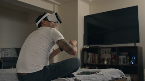 Man uses VR headset and controller for intense gaming session while sitting on bed at home