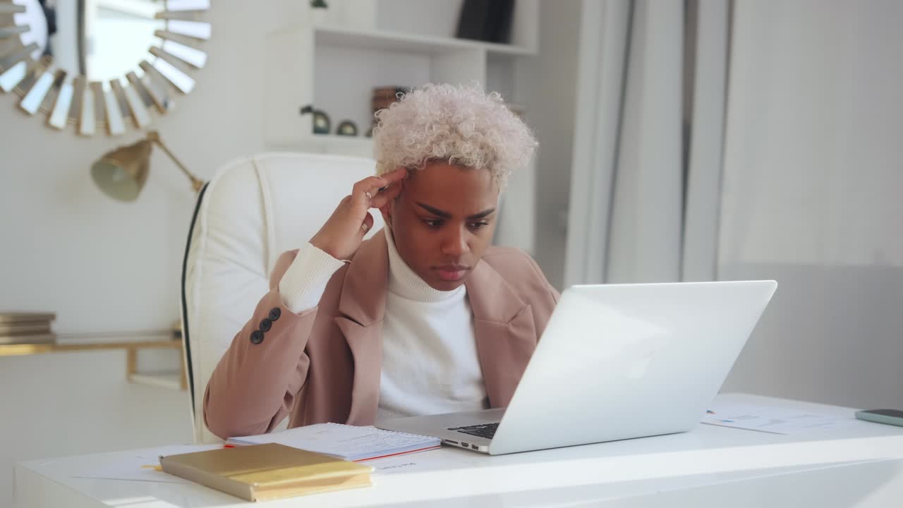 Ung afrikansk-amerikansk kvinde arbejder i en stor virksomhed og sidder på et kontor.