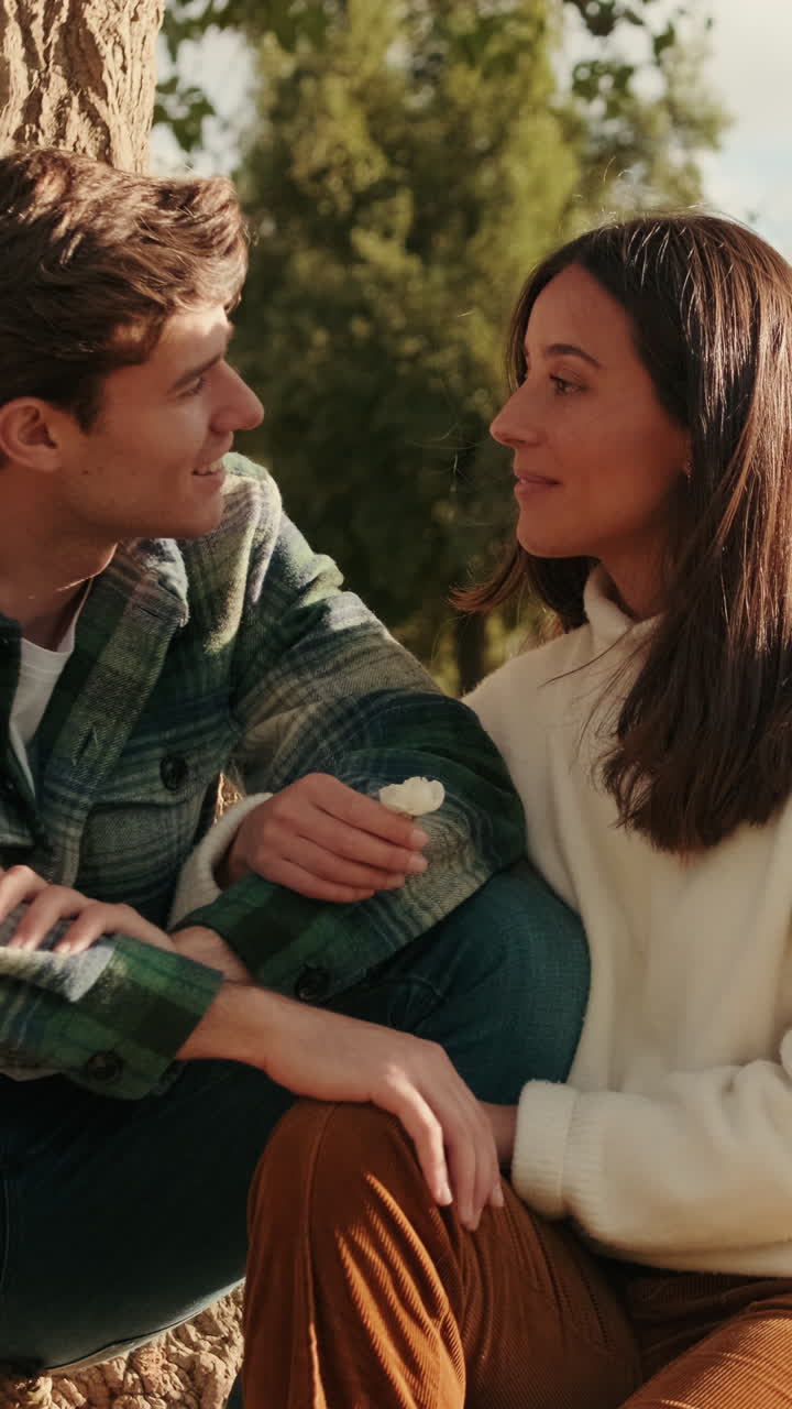 Happy young couple man and woman talking and laughing sitting in the park under