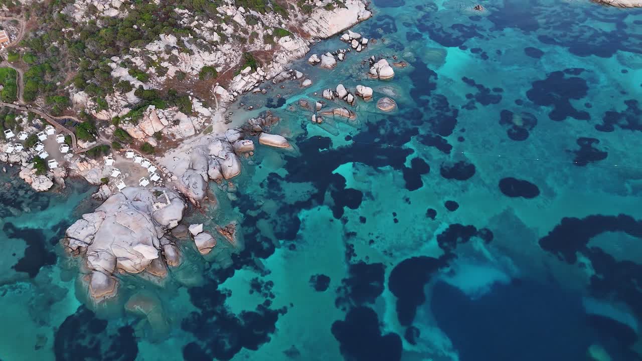 Aerial view of Sardinian coast with clear blue water and rocky shoreline