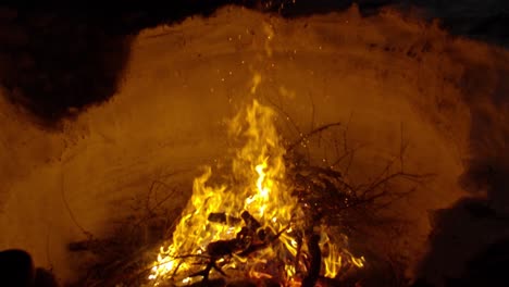 campfire burning in slow motion, the high frame rate shows the flames lingering around the wood, warming those who made it, melting the snow around