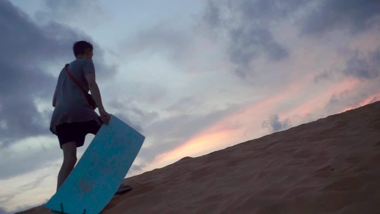 Tourist walking upwards a sand dune at a tourist attraction