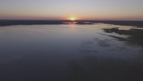 boats on calm lake at sunset