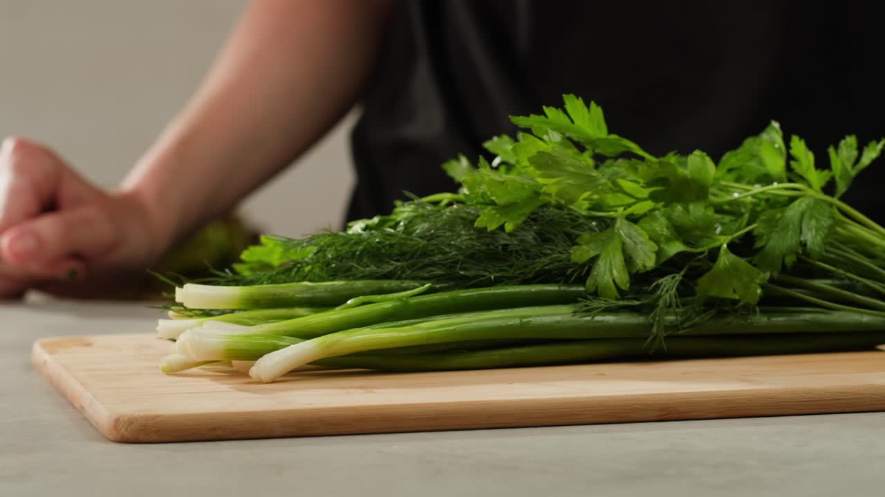 Cutting fresh green onions on a cutting board, close up chef cooking green vegan salad.