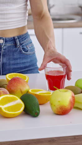 organic fruits ad fresh juice on the table. woman's hand is taking glass of fresh juice on the natural vitamins background. healthy lifestyle. vertical video