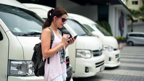 joven turista con teléfono inteligente esperando un autobús en una estación de autobuses, concepto de viaje y estilo de vida activo