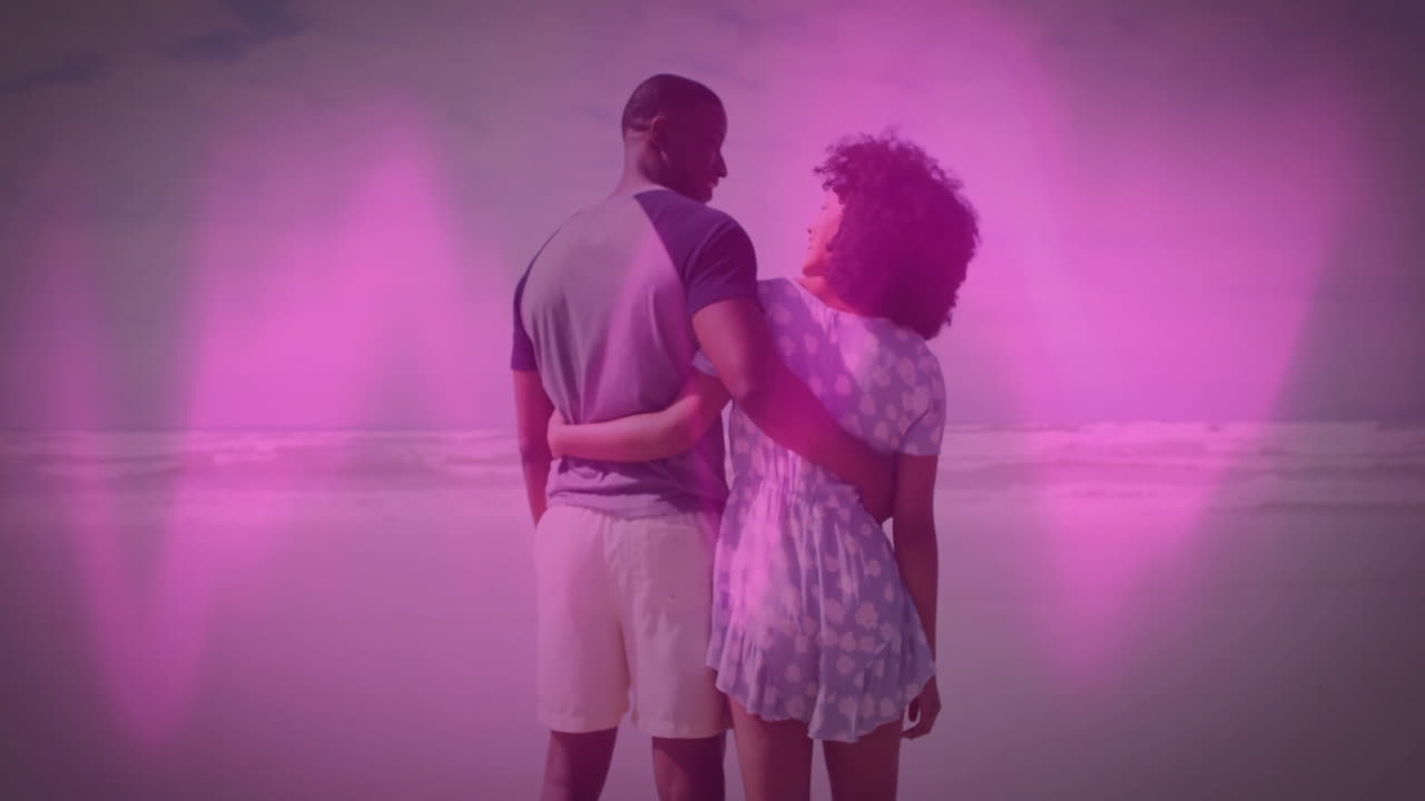 man and woman standing on beach shoreline, projecting pink overlay for digital marketing campaign