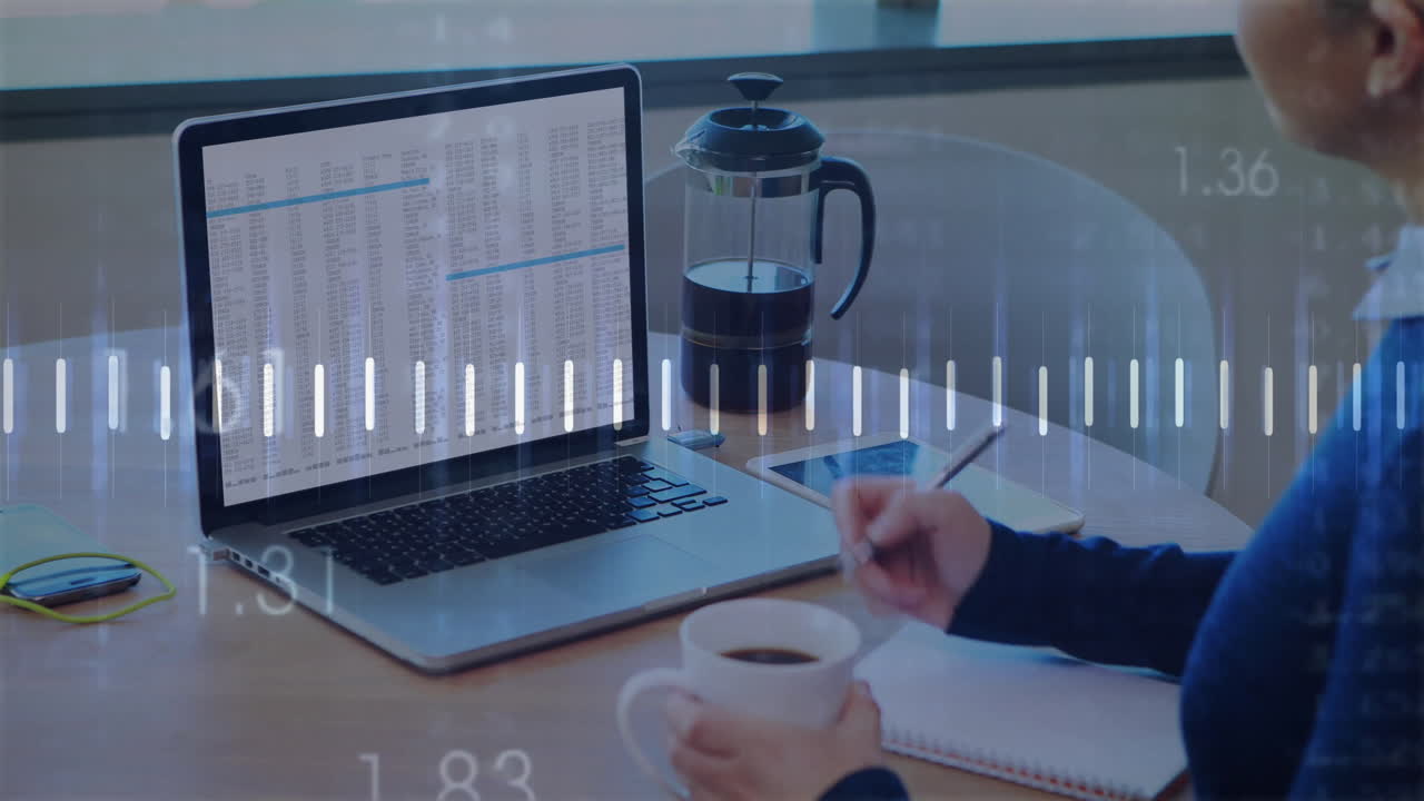 Person taking notes with coffee, laptop, and financial data animation overlay