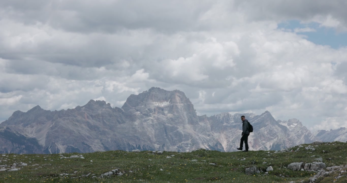 Un uomo cammina nell'area delle Cinque Torri a Cortina d'Ampezzo, Dolomiti, Italia, circondato da formazioni rocciose montane e paesaggio alpino.