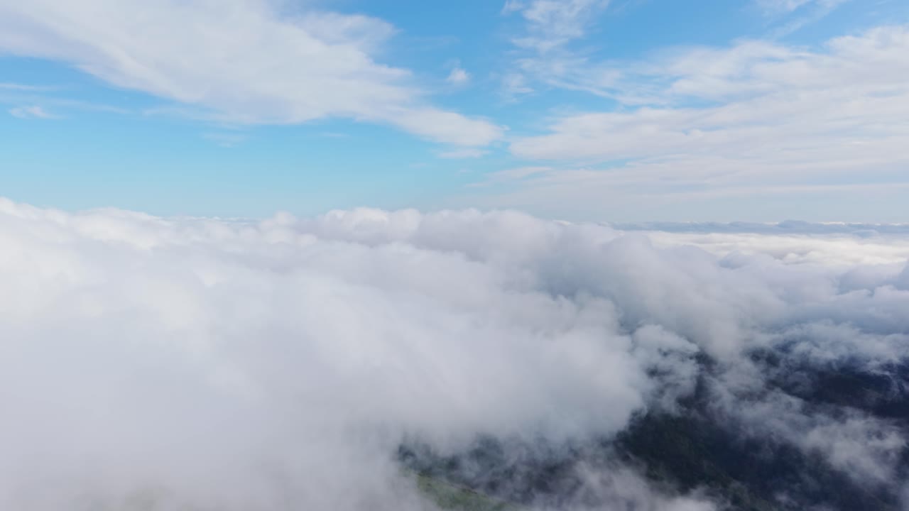 Big, fluffy clouds filling the sky with blue and sunlight in a peaceful aerial view
