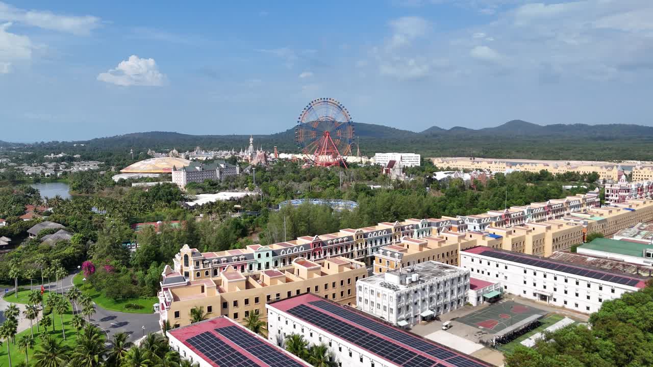 Aerial footage of an urban landscape with a blend of modern and historical architecture. A large Ferris wheel stands out for entertainment and leisure. Solar panels in the aerial view. Giant wheel.