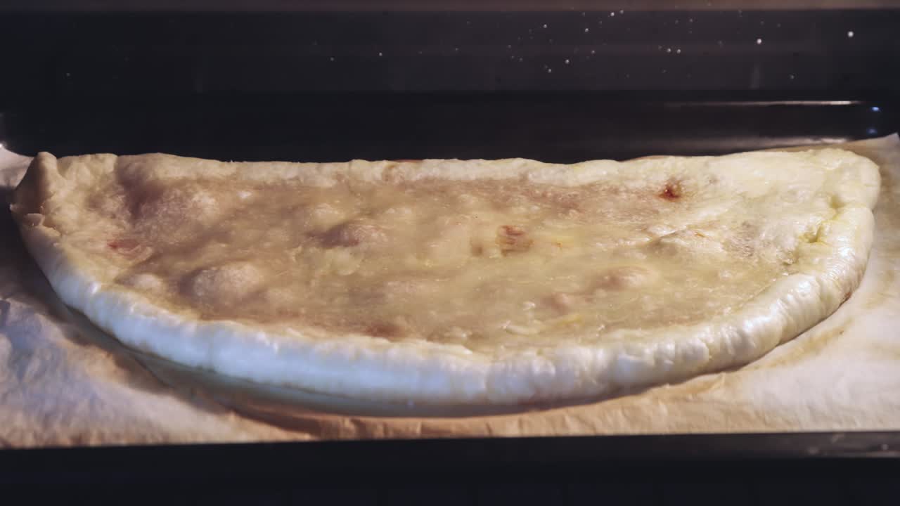 pizza calzone en el horno en papel de hornear, comida italiana