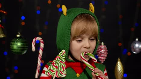 adorable niña elfa disfrutando de las golosinas de navidad