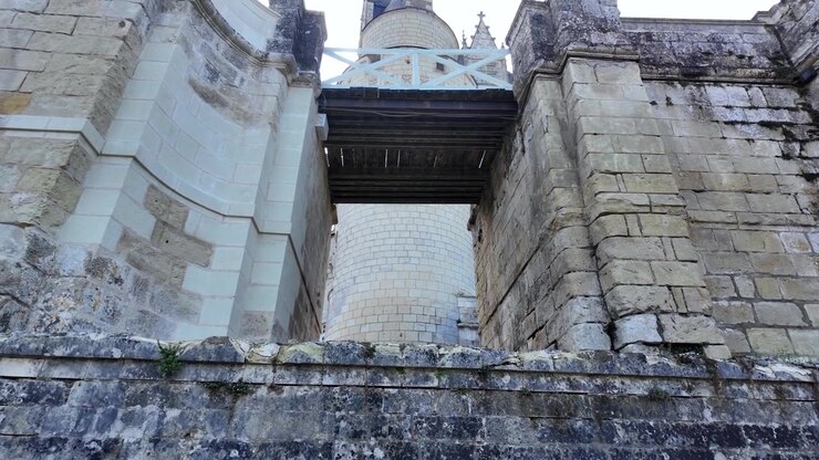 Un ponte di legno con ringhiere bianche collega pareti in pietra chiara sopra un muro in muratura usurato al Château d'Ussé, nella Valle della Loira, Francia.