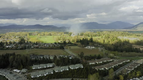 Roofs-of-suburban-homes-with-smoke-rising-in-the-distance