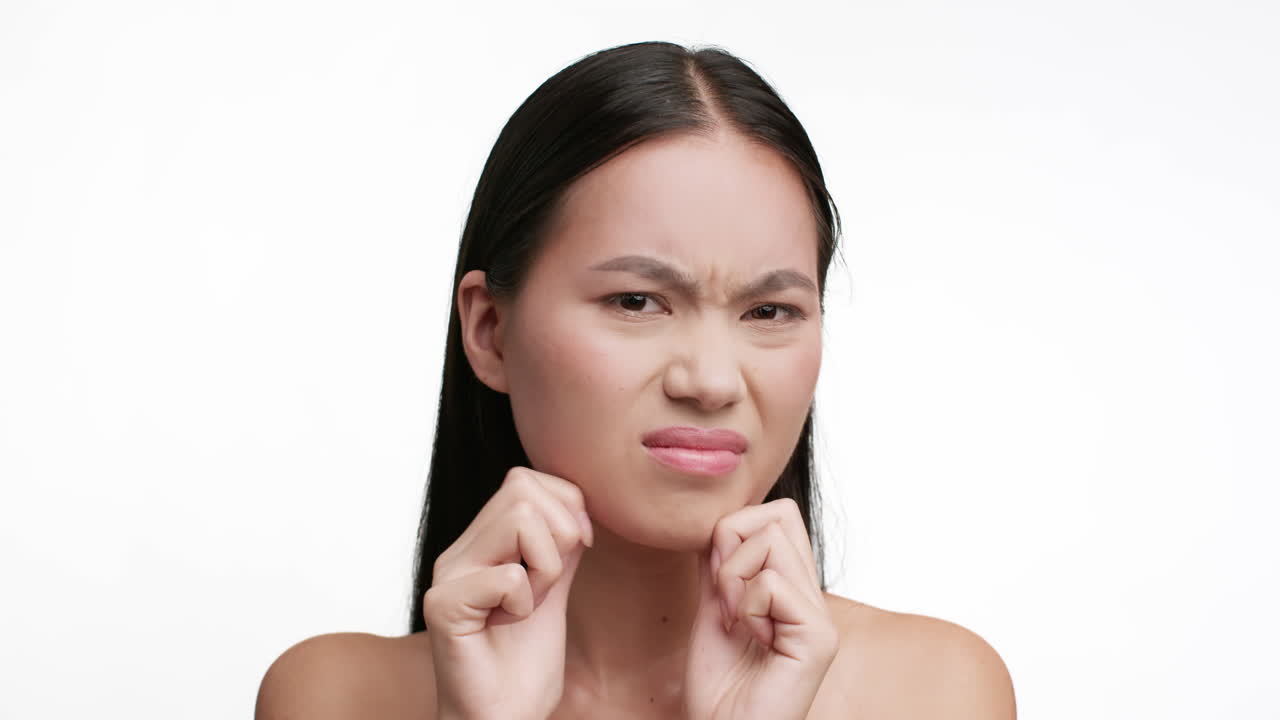 Young Asian woman expressing discomfort or contemplation while touching her face