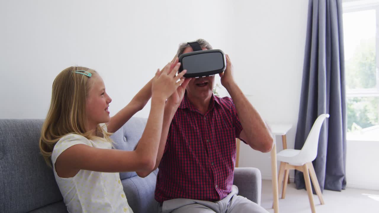 nieta caucásica ayudando a su abuelo a usar auriculares vr en casa