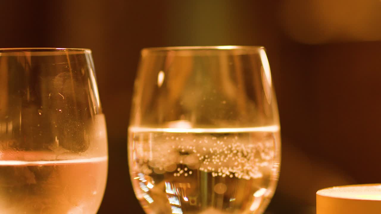 Close-up of sparkling water glasses on bar table, warm bokeh lighting, subtle camera movement