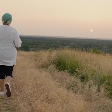 an elderly woman runs along a country road goes in for sports