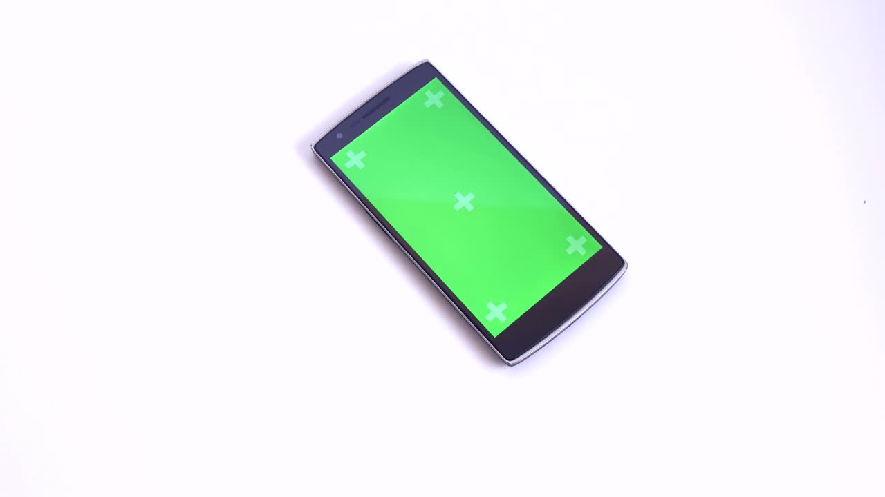 Hand Placing Smart Phone With Green Chroma Screen On White Table Closeup