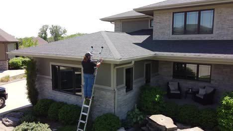 drone-opname van een gootinspectie vanaf een ladder door een handige timmerman