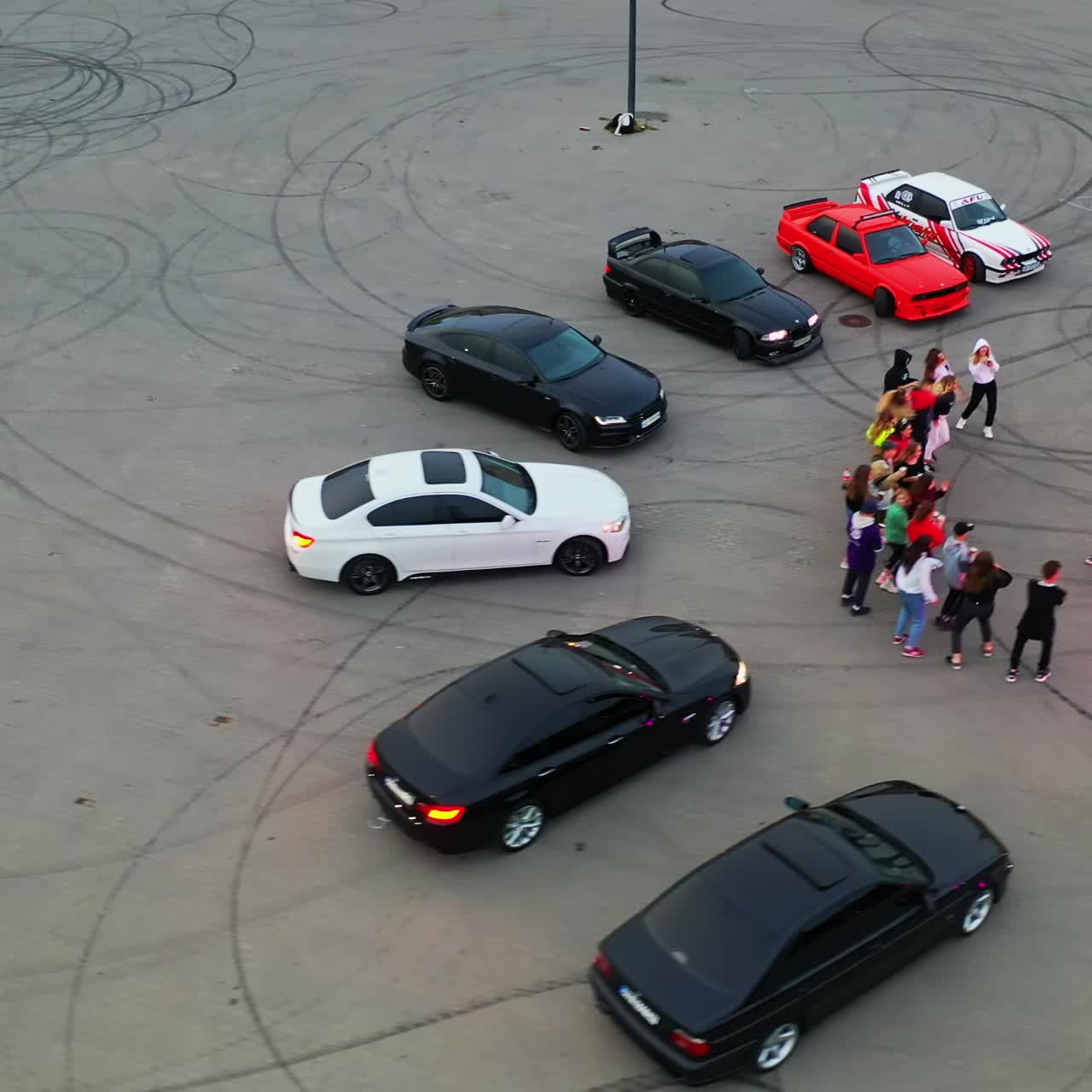 Hip hop dancers performing at the stadium for drift. Race cars are around the dancers. Top view