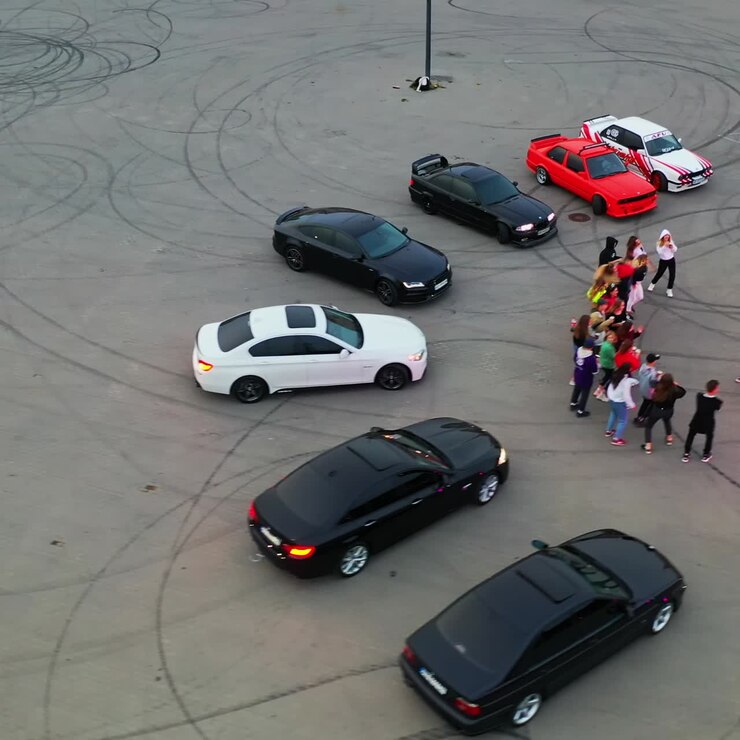 Bailarines de hip hop actuando en el estadio para drift. Coches de carreras alrededor de los bailarines. Vista superior