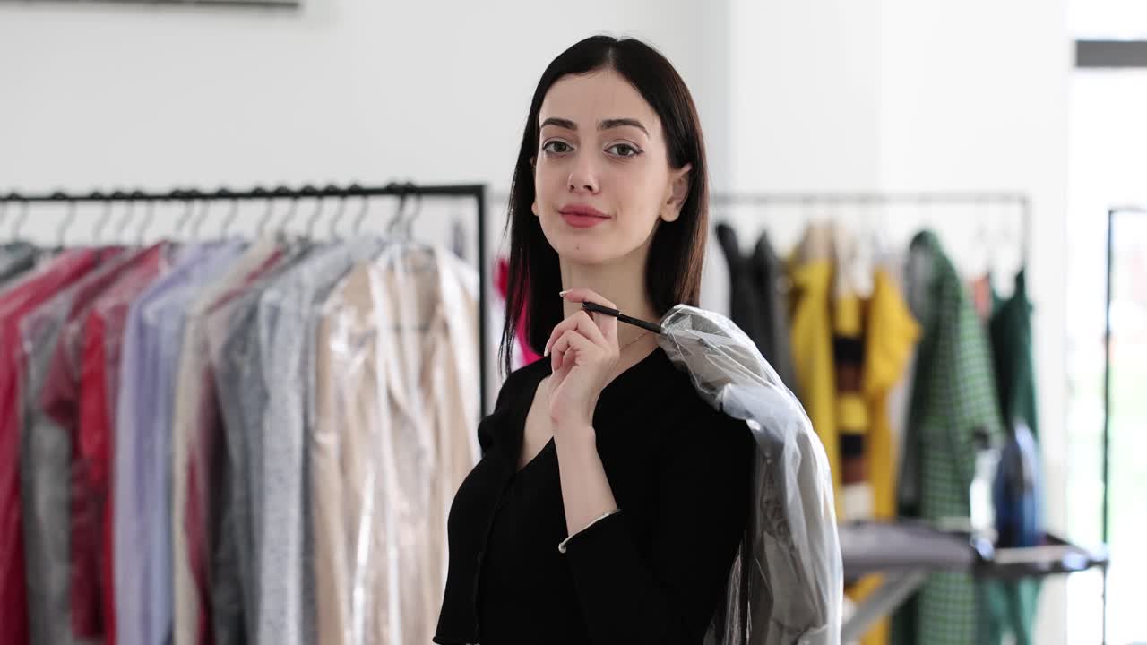 Woman holding cleaned clothes at a dry cleaning or laundry service