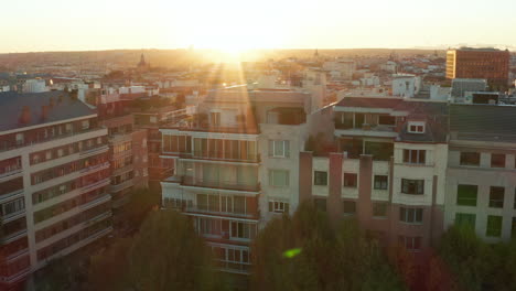 Slide-and-pan-footage-of-apartment-houses-in-town.-Large-city-in-background.-View-against-setting-sun.