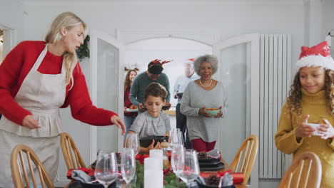 multi-generation family bringing food into dining room for christmas meal