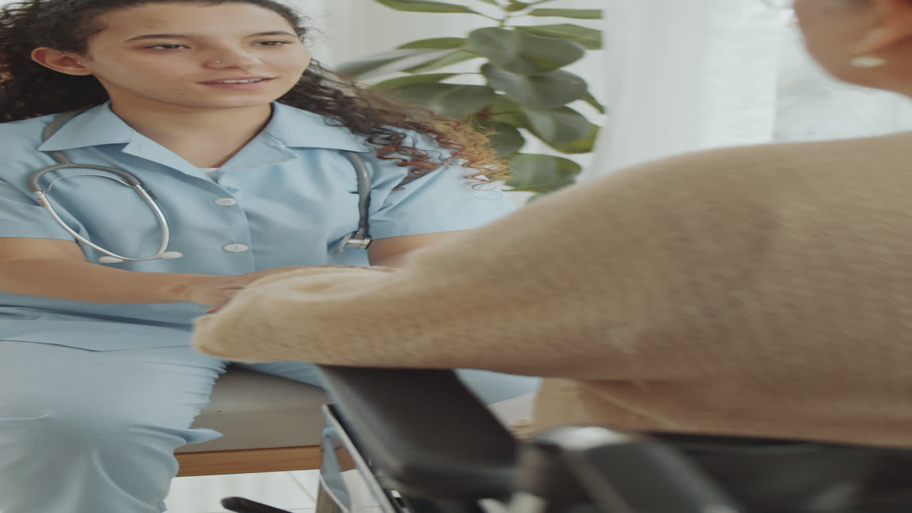 Female Doctor Holding Hands and Talking with Patient in Wheelchair