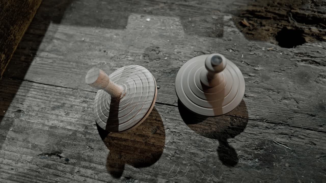 Two wooden children's spinning tops rotate then stop on workshed bench