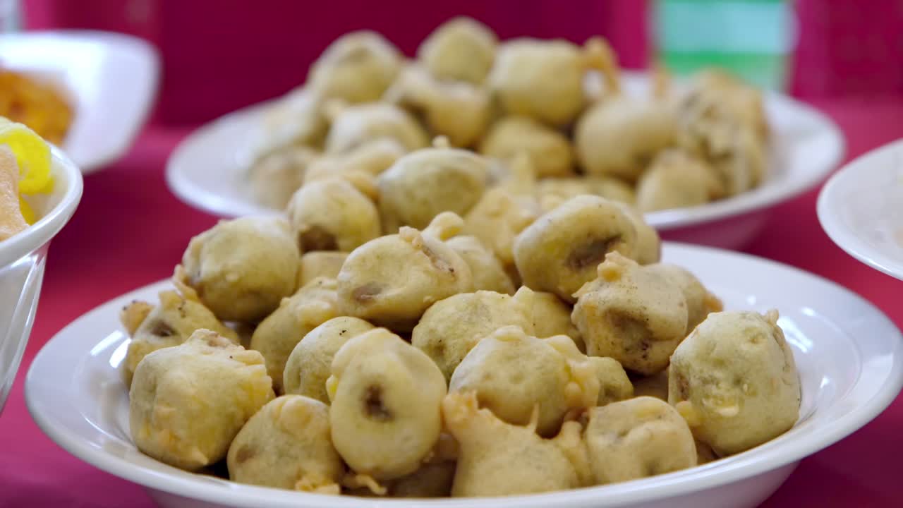 Delicious golden Aloo Bonda served in a bowl at an Indian wedding buffet. Crispy fried snack filled with spiced potato, showcasing vibrant South Asian cuisine and celebration