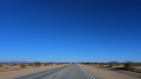 Conduciendo-Por-El-Desierto-De-Mojave-En-Un-Día-Brillante-Con-Un-Cielo-Azul-Claro---Punto-De-Vista-Hiper-Lapso