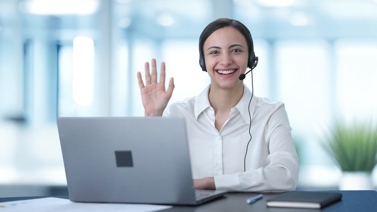 chica feliz del centro de llamadas indio saludando a la cámara