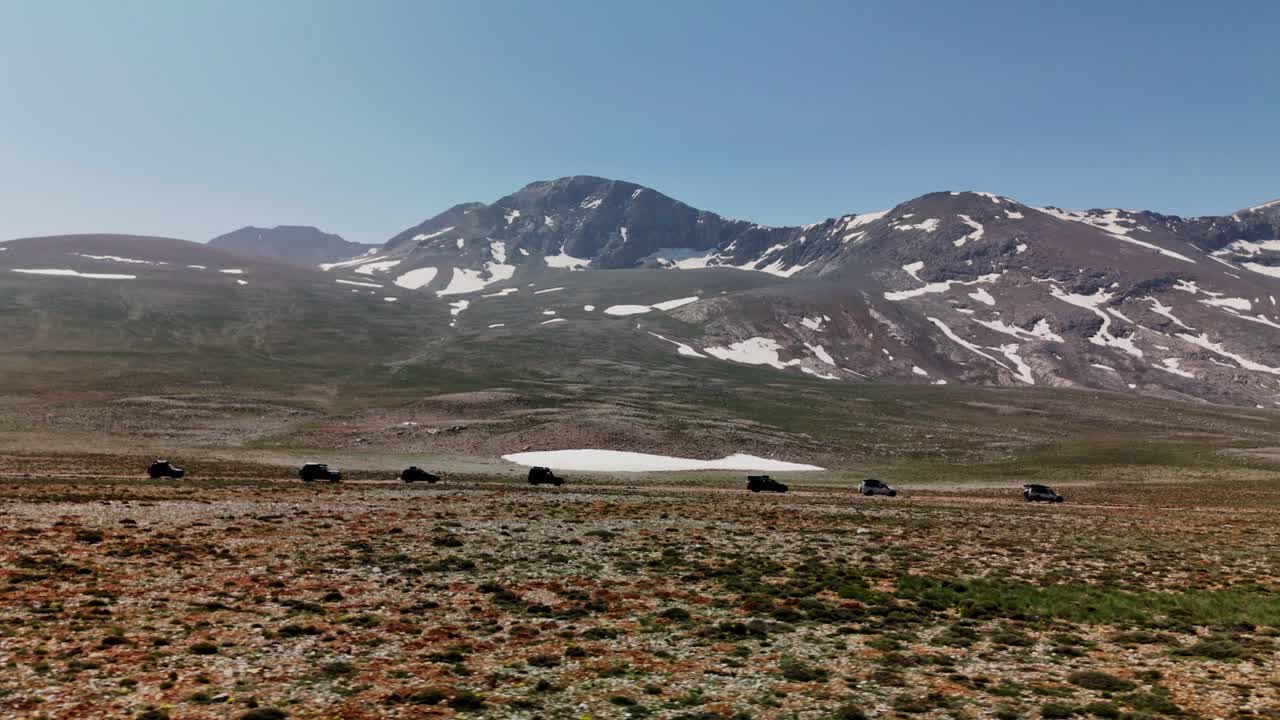 Cars drive across Cappadocia's scenic mountains in daylight adventure