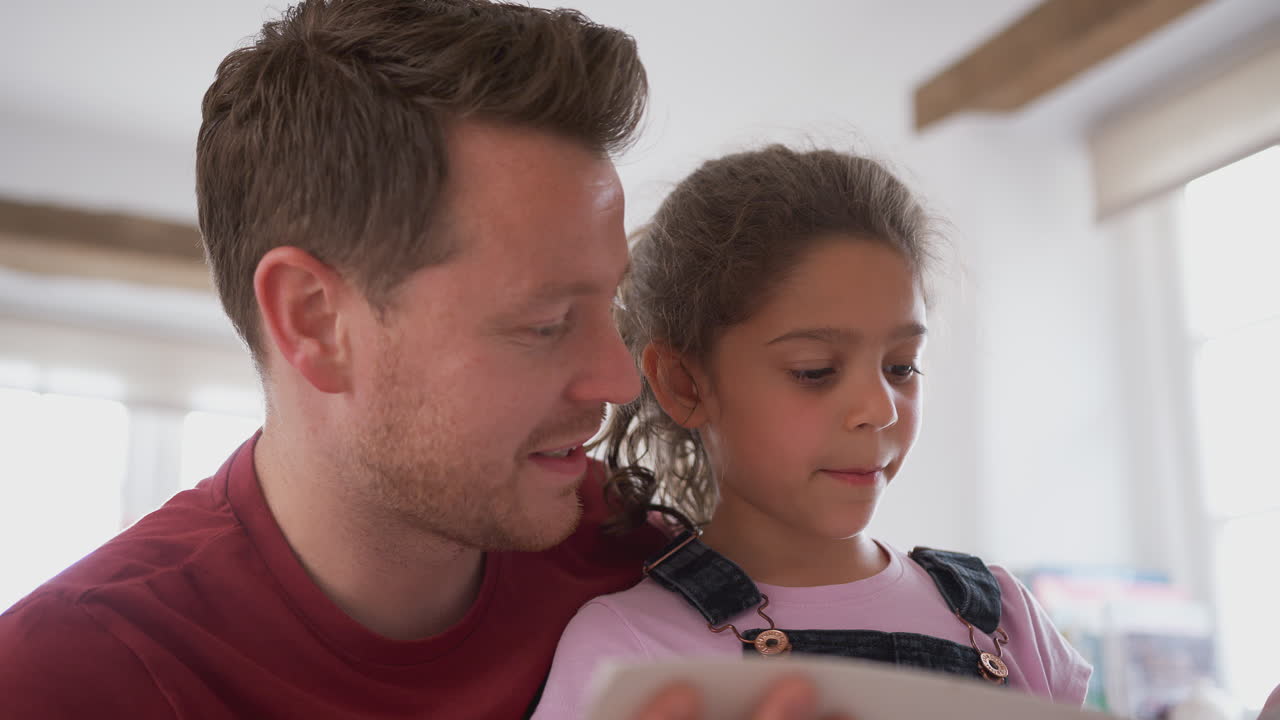 padre e hija en el dormitorio leyendo un libro juntos