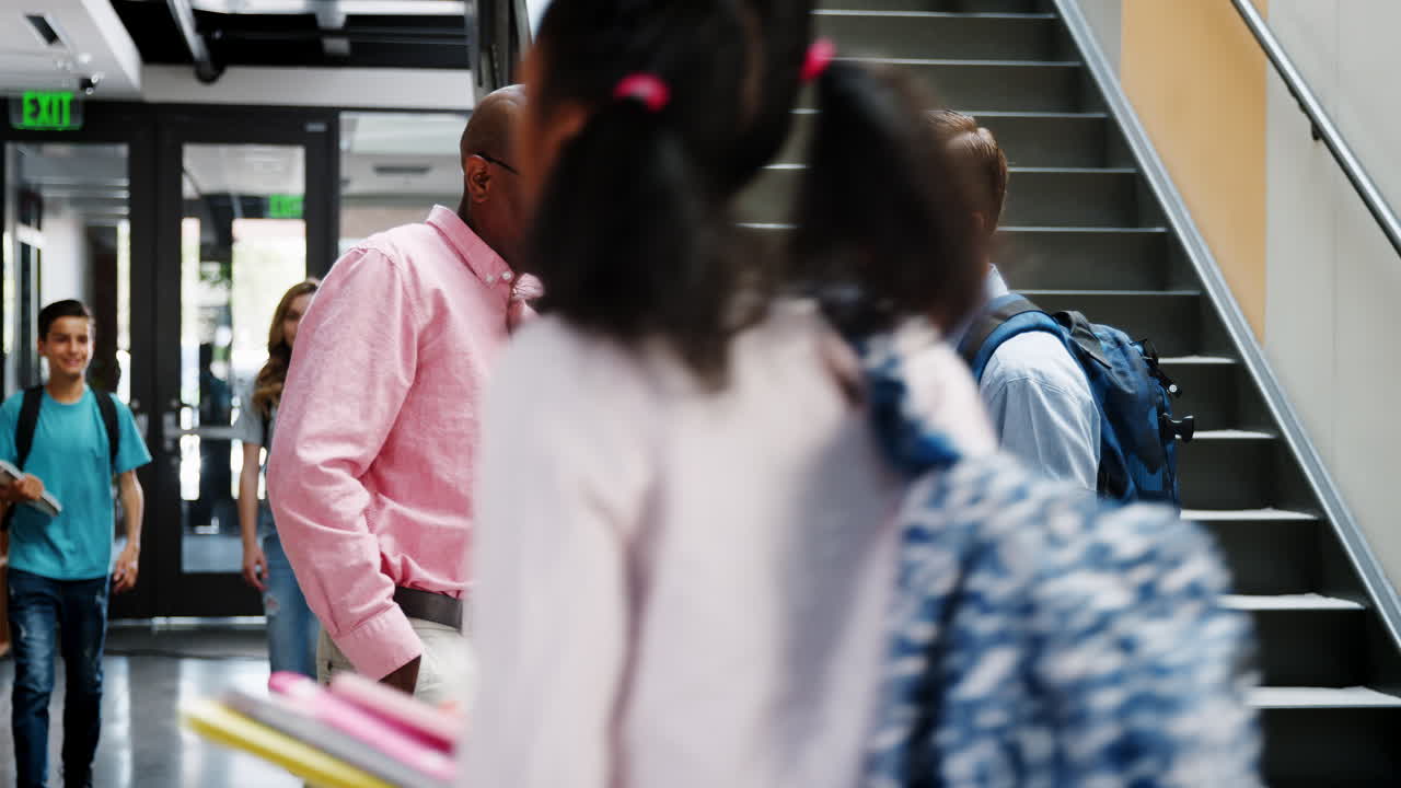 남자 고등학교 학생 이 바쁜 복도 에서 교사 와 대화 하고 있다
