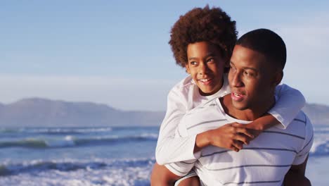 Afroamerikanischer-Vater,-Der-Seinem-Sohn-Am-Strand-Eine-Huckepackfahrt-Gibt