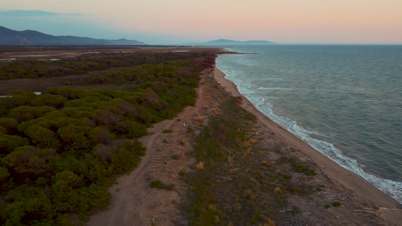 imágenes cinematográficas de drones aéreos de gran altitud sobre una playa de arena al atardecer en la costa cerca de alberese en el icónico parque natural maremma en toscana, italia, con olas, islas y un espectacular cielo rojo