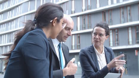 business team watching presentation on laptop, discussing project while sitting together at office building