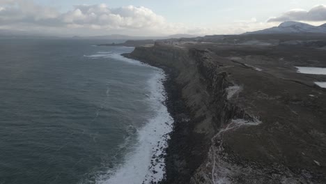 Rugged-cliffs-of-Kilt-Rock-under-cloudy-skies-along-the-Isle-of-Skye-coastline,-Scotland,-with-a-tranquil-sea